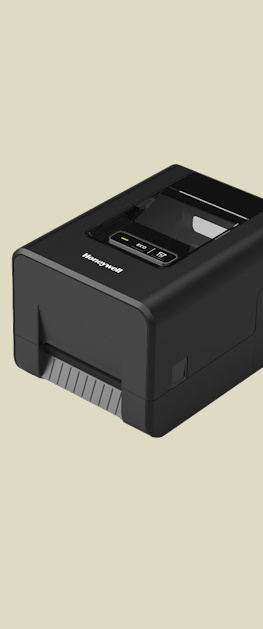 En Honeywell PC42E-T desktop etikettskriver sett sideveis forfra på en brun bakgrunn.