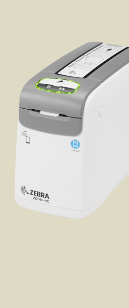 En Zebra ZD510-HC desktop armbånds etikettskriver sett sideveis forfra på en brun bakgrunn.