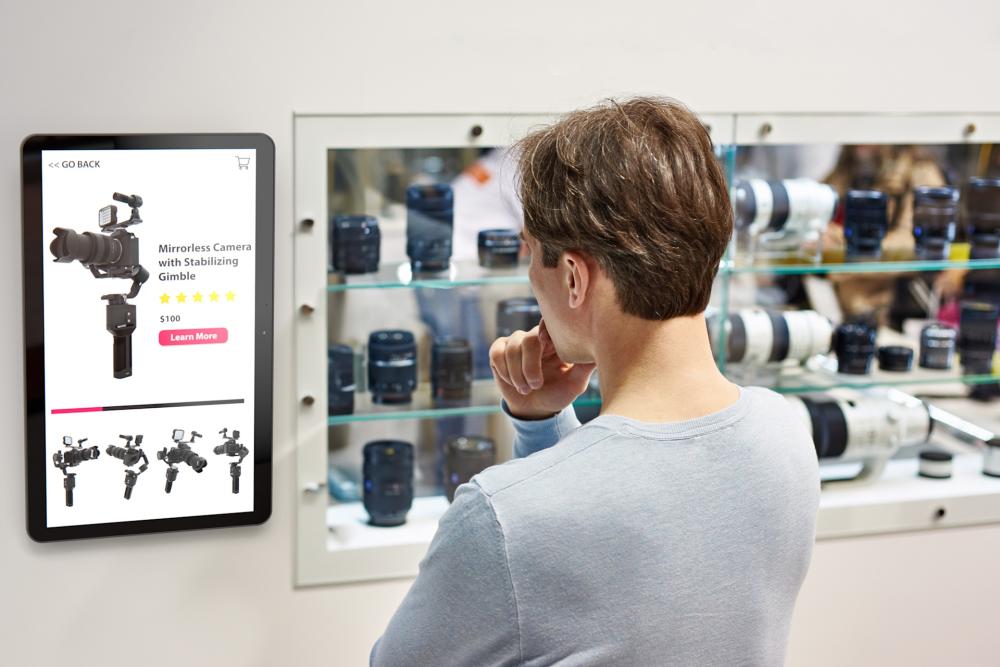 Mann som jobber p&aring; en b&aelig;rbar PC ved et bord, med en Zebra ZD421 etikettskriver ved siden av og ruller av stoff i bakgrunnen