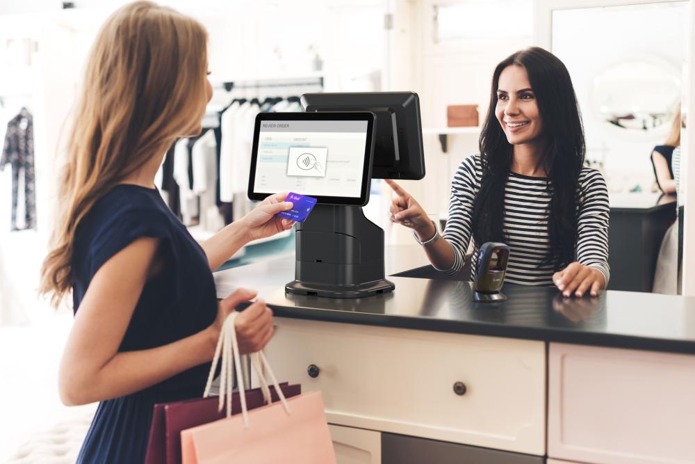 Mann som jobber p&aring; en b&aelig;rbar PC ved et bord, med en Zebra ZD421 etikettskriver ved siden av og ruller av stoff i bakgrunnen