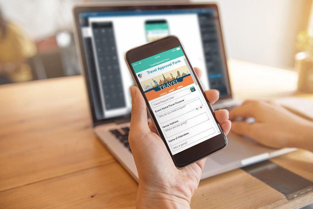 Kvinne bruker SOTI Snap-app på mobiltelefon foran en bærbar datamaskin.