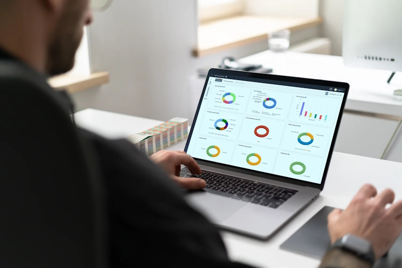 En person bruker en laptop for å se på en rekke komplekse dataanalyser og grafer, som demonstrerer ytelsesstatistikk og overvåkingsdata for forretningsdrift.